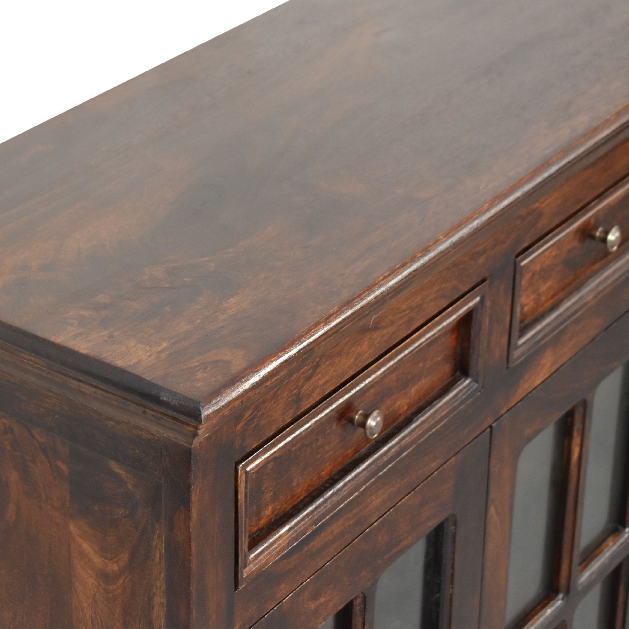 Wooden cabinet close-up with drawers and brass handles.